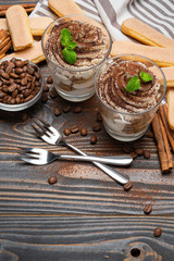 two portions Classic tiramisu dessert in a glass on wooden background