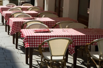 Conceptual empty restaurant tables with red checkered tablecloth.