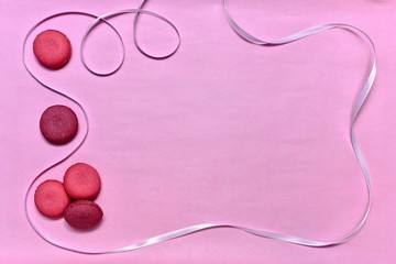 Five cookies left on a pink background. With a white satin ribbon in the form of a frame.