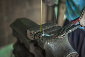 Worker with protective gloves welding metal part in workshop