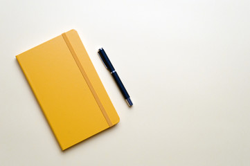 Notebook and pen on yellow background