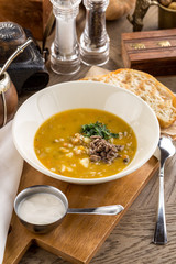 Fresh homemade vegetable soup with peas, potatoes garnished with fresh parsley and meat on rustic wooden board
