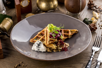 Savory waffles with mushroom and creamy sauce on plate on a wooden table