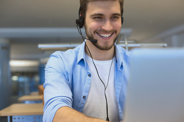 Happy young male customer support executive working in office.