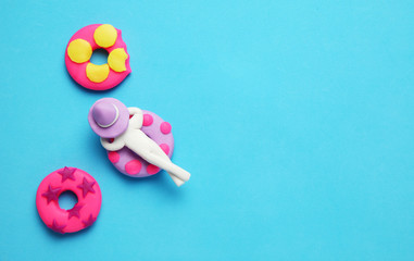 Plasticine people relaxing on inflatable donut lilo in pool. Cartoon summer relaxing and holidays.