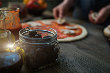 Pizza art. The process of making pizza. Raw dough for pizza with ingredients and spices on table. Traditional Italian pizza and vegetables on a dark wooden background. Pizza menu. Soft focus.