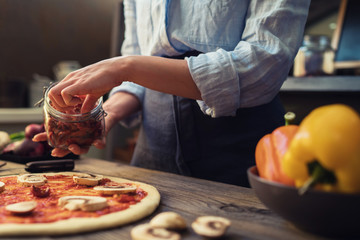 Fresh pizza with tomato and mushrooms. Homemade tasty pizza on dark wooden background. Raw dough for pizza with ingredients and spices on wooden rustic table. Traditional Italian food. Soft focus.