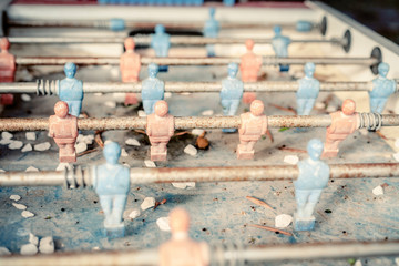 A rusty, dirty, abandoned table football game. Detail shot of the corroded plastic and metal parts, with debris left over the surface.