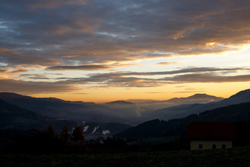 sunrise in the austrian alps shining at mystic clouds up a sleeping valley in styria in the...