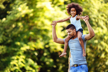 Fototapeta premium Portrait of young father carrying his daughter on his back