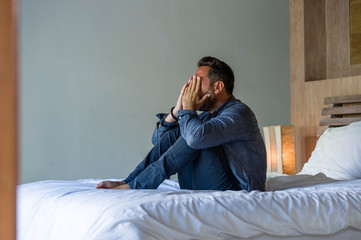 young attractive stressed and depressed man sitting on bed worried and frustrated suffering...