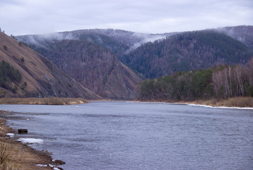 hilly coast of the Siberian river in the fog