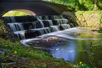 Bridge and water threshold over a small river in a park in the city of Poznan.
