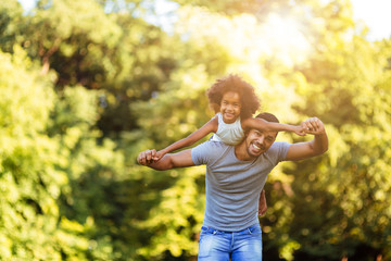 Obraz premium Portrait of young father carrying his daughter on his back
