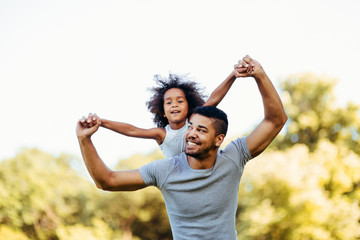 Portrait of young father carrying his daughter on his back