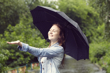 cheerful woman with an umbrella walking in the rain