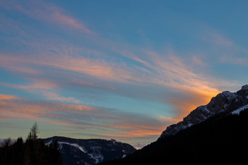 Obraz premium colorful sunset with glowing clouds above mountain tops in the austrian alps in winter