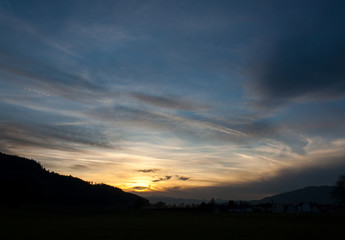 mystic sunset in the austrian alps with mighty clouds in front of the sun