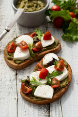 Healthy food. Flat lay of toast sandwich with mozzarella, cherry tomatoes and pesto, light wooden background. Healthy breakfast, snack. Copy space