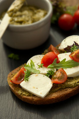 Mozzarella cheese, cherry tomatoes and pesto bruschetta, toast on wooden background. Healthy breakfast ,snack. Pesto pasta.