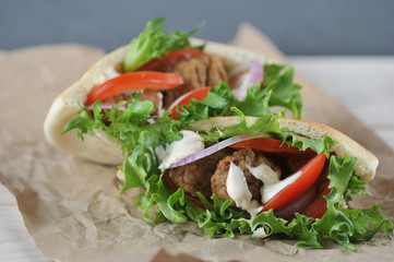 Falafel in pita bread with tomatoes, lettuce and sauce occupies the entire frame space. Background craft paper. Close-up. Macro shooting.
