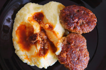 Meat patties and mashed potatoes on a plate. Close-up. View from above. Background.