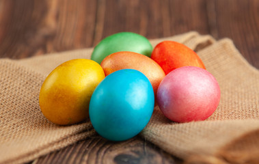 Obraz na płótnie Canvas Colored Easter eggs on a wooden background on burlap