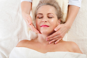 portrait of beautiful woman in spa environment. middle aged woman doing facial massage in a spa salon