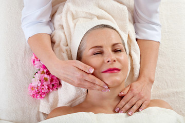 Fototapeta na wymiar portrait of beautiful woman in spa environment. middle aged woman doing facial massage in a spa salon