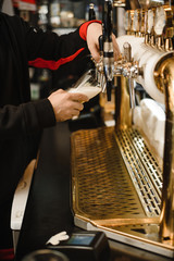 hands of man pouring beer. Golden metal tap in ice with frothy drink. A tasteful ale in a mug. hands of man pouring beer. Golden metal tap in ice with frothy drink. Delicious ale in the mug. Beer at b