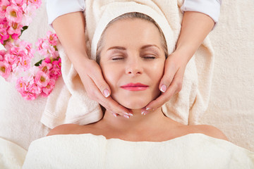 Fototapeta na wymiar portrait of beautiful woman in spa environment. middle aged woman doing facial massage in a spa salon
