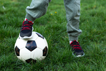 Fototapeta premium a football and legs of a small boy green grass