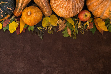 Autumn background with yellow leaves, red apples and pumpkins. Border of fall harvest on aged wood...
