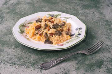 Homemade rice stew with chicken livers and chorizo, in green porcelain dish on green marbling background