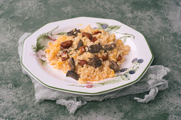 Homemade rice stew with chicken livers and chorizo, in green porcelain dish on green marbling background