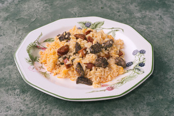 Homemade rice stew with chicken livers and chorizo, in green porcelain dish on green marbling background
