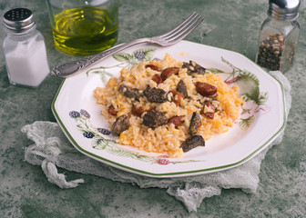 Homemade rice stew with chicken livers and chorizo, in green porcelain dish on green marbling background
