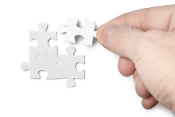 Hand inserting missing piece of a blank puzzle, isolated on white background