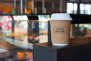 closeup have a nice day message on paper cup of coffee in cafe with soft-focus and over light in the background