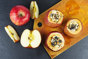 Stuffed baked apples with sezame seeds and walnuts over the black slate stone background