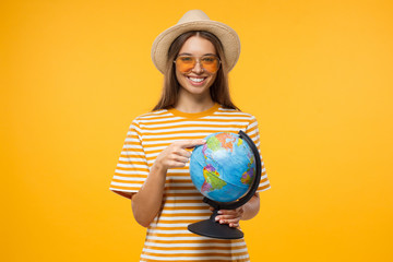 Travel agency advertising. Choosing place to be concept.  Young female tourist holding globe with...
