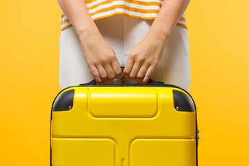 Close-up shot of woman holds yellow suitcase with both hands