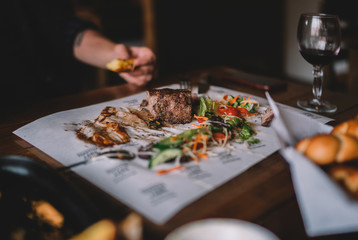 Eating and leisure concept. Enjoying dinner. People having dinner on the table. Assorted delicious vegetables with grilled meat. Toned image. Selective focus.