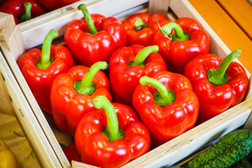 Bright red, fresh paprikas in a wooden box in a shop