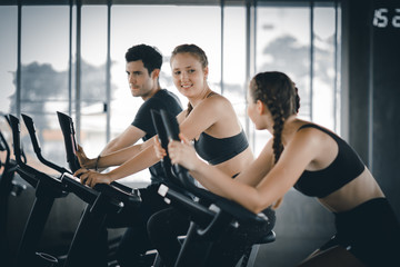 Fototapeta na wymiar Group of people biking in the gym, exercising legs doing cardio workout cycling bikes. Couple in a spinning class wearing sportswear. Fitness, Healthy, Sport, Lifestyle concept.v