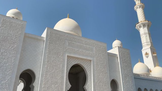 Main entrance of Sheik Zayed Mosque with its beautiful ornamented walls and white domes above it.