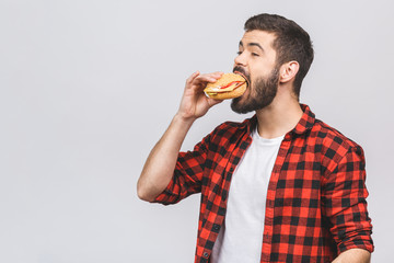 Young man holding a piece of hamburger. Student eats fast food. Burger is not helpful food. Very hungry guy. Diet concept isolated against white background.