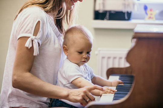 Mother and toddler baby boy, playing piano at home