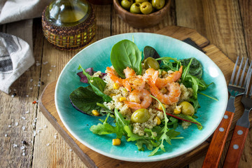 Diet menu, Vegan food. Healthy salad with quinoa, arugula, Shrimps and olives on a wooden rustic table. Copy space.
