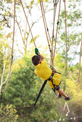 Asean boy nodes the rope and smiling happily in camp adventure Background blurry tree.